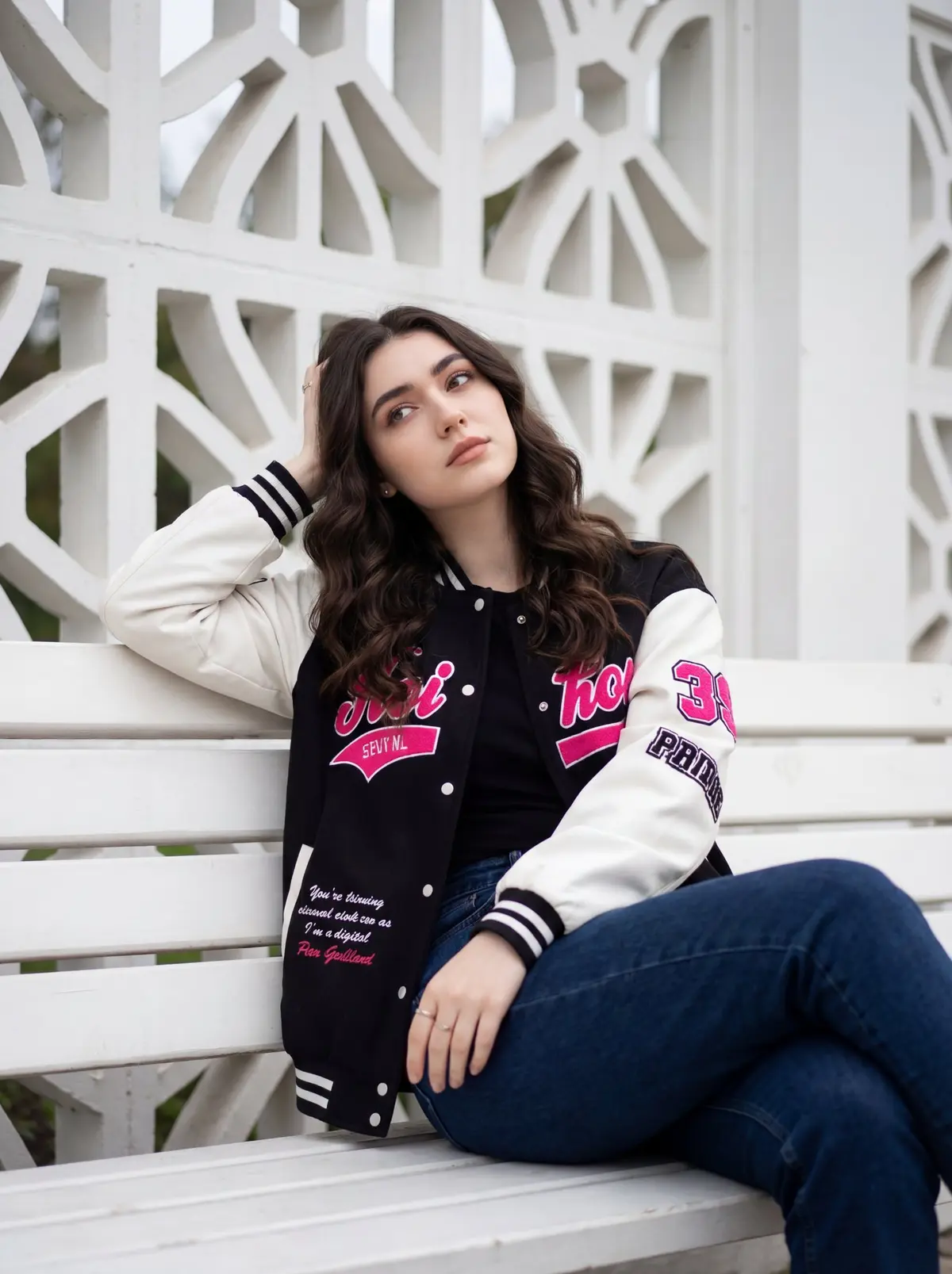 A young woman is sitting casually on a white wooden bench, p