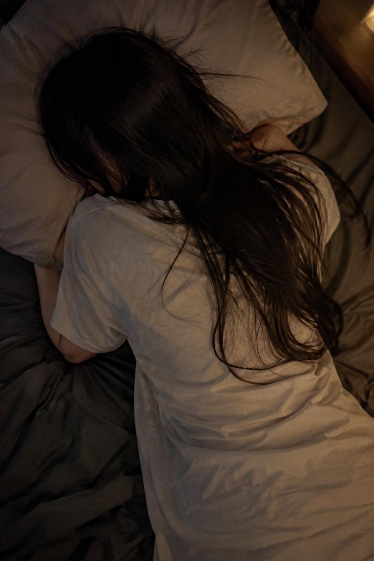 Overhead bedroom smartphone portrait in a white oversized T-shirt