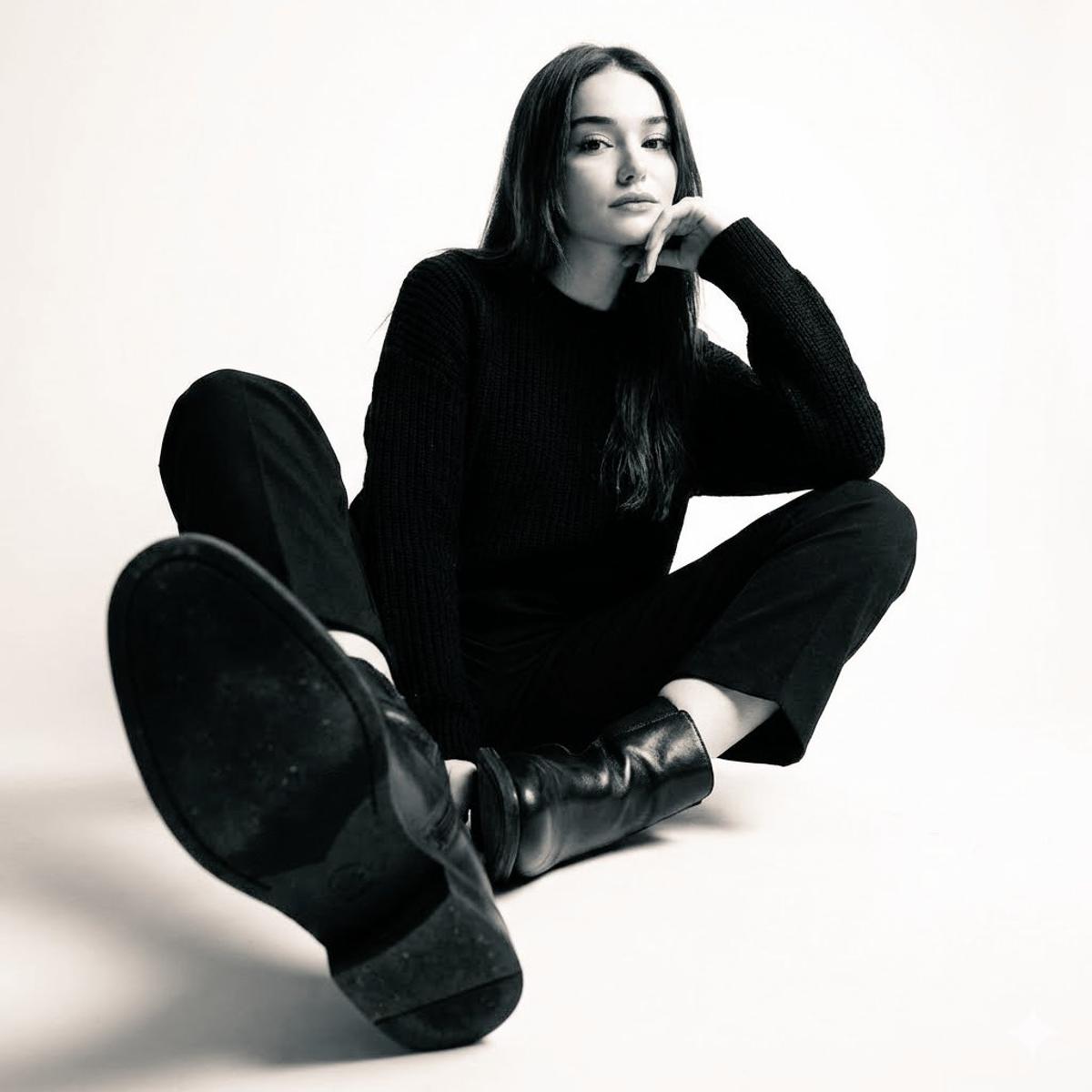 High-contrast black-and-white studio photo of a woman seated